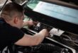 Mekanik sedang melakukan perawatan klakson mobil di area mesin kendaraan untuk memastikan fungsinya optimal