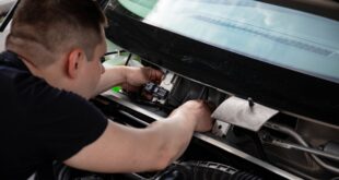 Mekanik sedang melakukan perawatan klakson mobil di area mesin kendaraan untuk memastikan fungsinya optimal